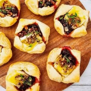 These Puff Pastry Cranberry Brie Bites are an easy holiday appetizer for entertaining. Flaky puff pastry is filled with creamy Brie cheese, sweet-tart cranberry sauce, crunchy pecans, and fresh thyme, then baked until golden and perfectly melty. This Cranberry Brie Bites recipe is perfect for Christmas appetizers, Thanksgiving appetizers, holiday party food, New Year's Eve appetizers, and easy finger foods for entertaining. If you love baked Brie, puff pastry appetizers, cranberry appetizers and Brie recipes, these bite-sized treats are a must-try. With just 5 ingredients and 15 minutes of prep, these easy holiday appetizers look elegant without the extra work. Save these Cranberry Brie Puff Pastry Bites for your next holiday gathering, potluck, Christmas dinner, or party!