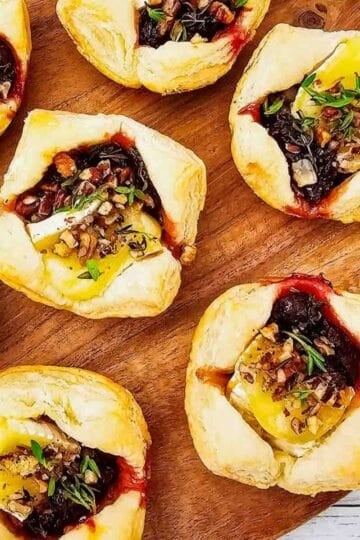 These Puff Pastry Cranberry Brie Bites are an easy holiday appetizer for entertaining. Flaky puff pastry is filled with creamy Brie cheese, sweet-tart cranberry sauce, crunchy pecans, and fresh thyme, then baked until golden and perfectly melty. This Cranberry Brie Bites recipe is perfect for Christmas appetizers, Thanksgiving appetizers, holiday party food, New Year's Eve appetizers, and easy finger foods for entertaining. If you love baked Brie, puff pastry appetizers, cranberry appetizers and Brie recipes, these bite-sized treats are a must-try. With just 5 ingredients and 15 minutes of prep, these easy holiday appetizers look elegant without the extra work. Save these Cranberry Brie Puff Pastry Bites for your next holiday gathering, potluck, Christmas dinner, or party!