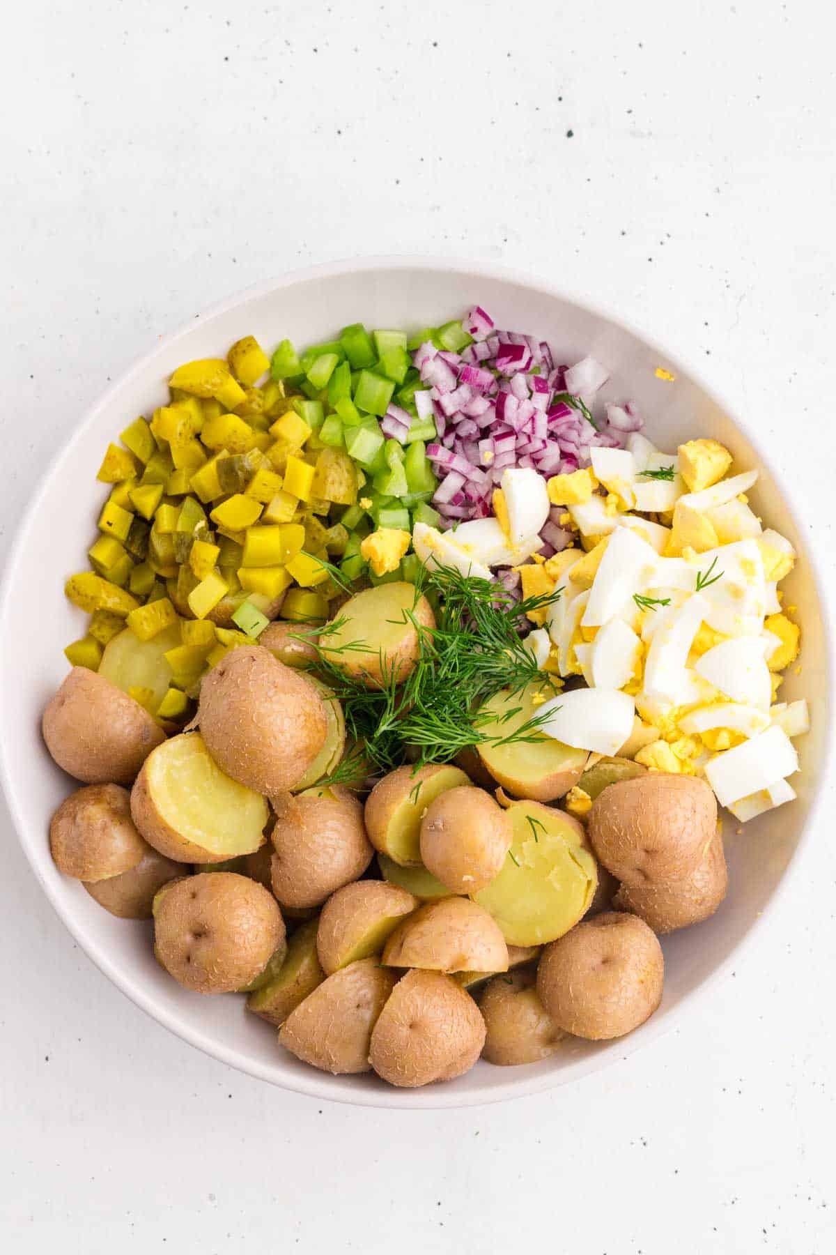 dill pickle potato salad ingredients in a mixng bowl
