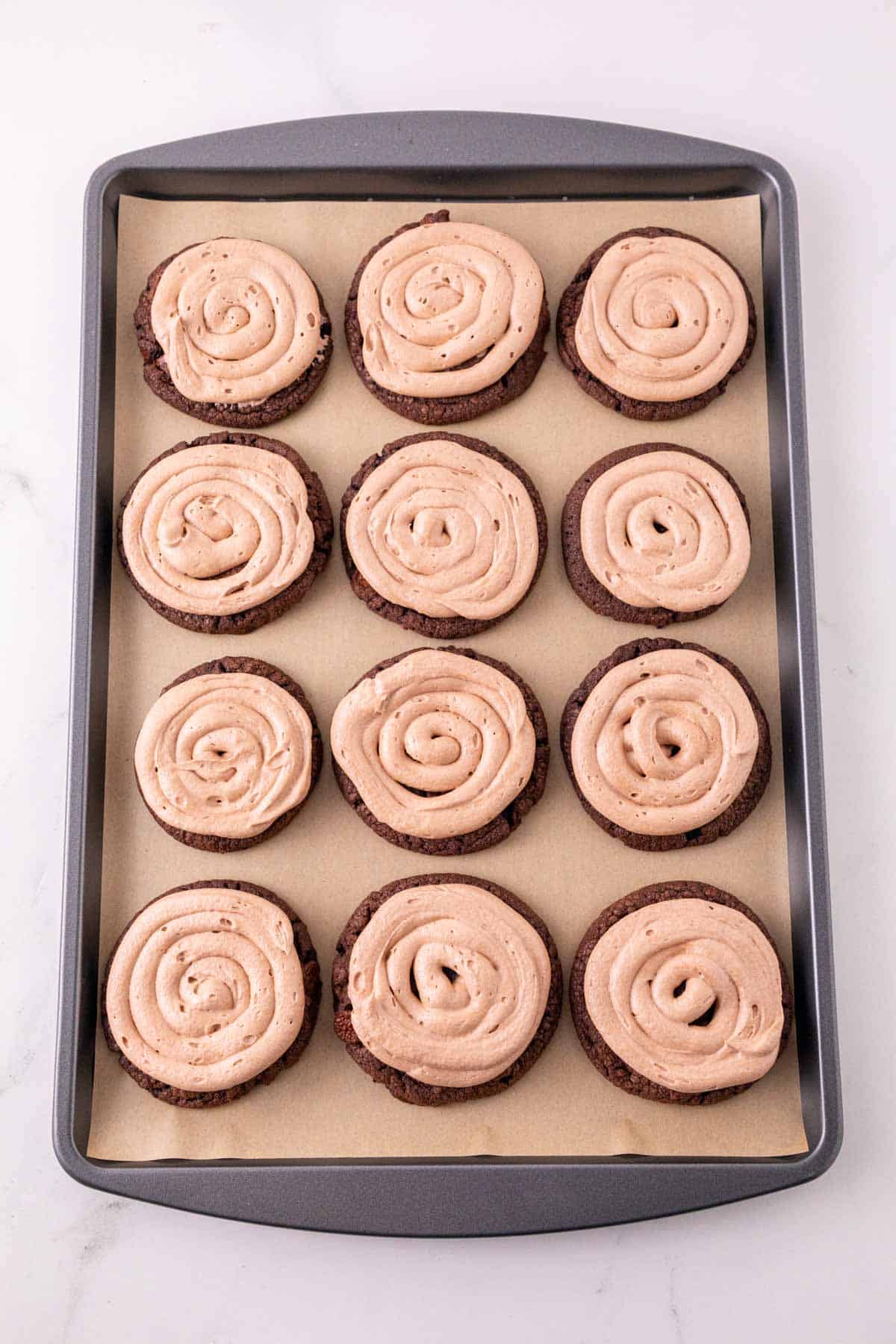 nutella frosting on top of chocolate cookies on a baking sheet