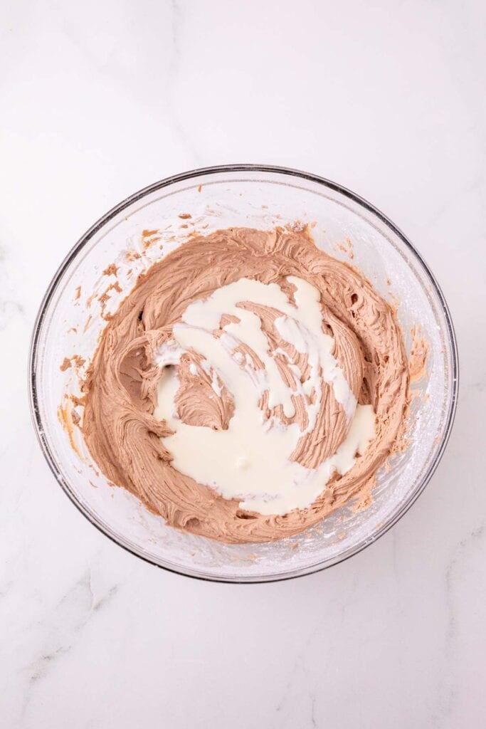 heavy cream added to nutella frosting mixture in a mixing bowl