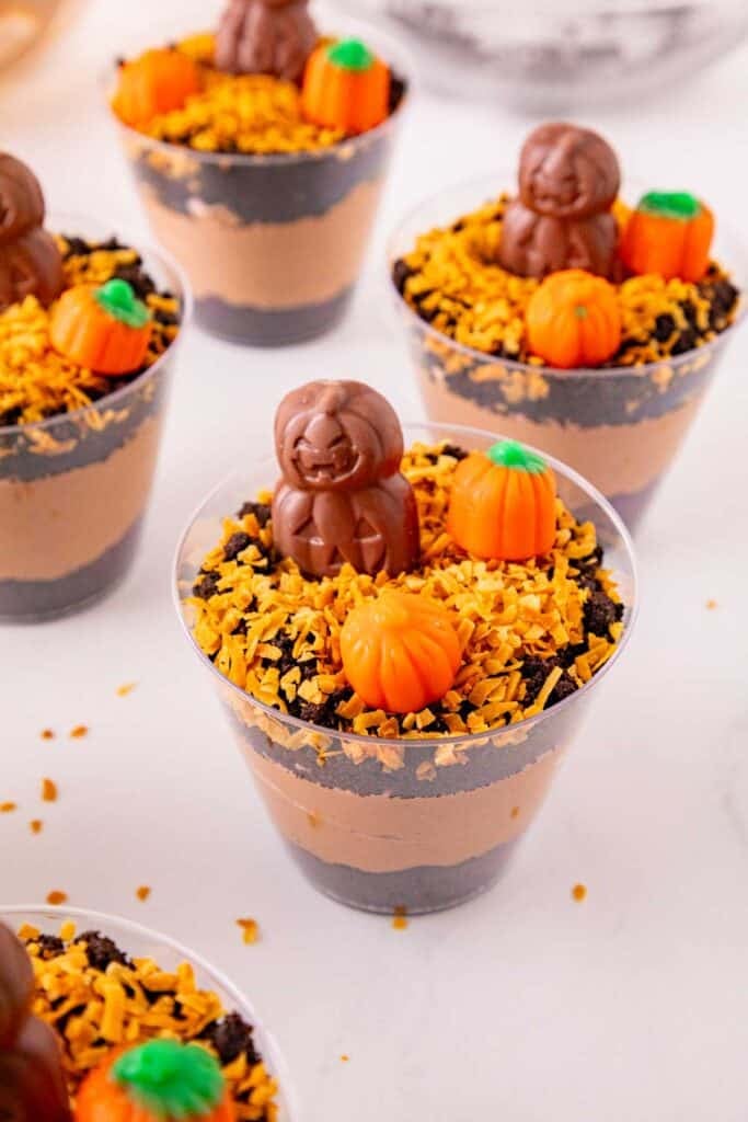 These Halloween Dirt Cups are an easy no bake Halloween dessert perfect for parties, kids, and spooky season celebrations! Creamy chocolate peanut butter pudding is layered with crushed Oreo cookies to create delicious Oreo dirt cups, then topped with toasted coconut, mellowcreme pumpkins, and jack o lantern chocolates. If you need easy Halloween desserts, Halloween party food, Halloween treats for kids, or fun Halloween dessert ideas, these pudding dirt cups are a must-try. These Halloween pudding cups take just 15 minutes to prepare and are served in individual cups for an easy party dessert. Make these spooky dirt cups for a Halloween party, school celebration, fall gathering, or movie night. They're a fun twist on classic Oreo dirt pudding and an easy Halloween treat everyone will want to dig into!