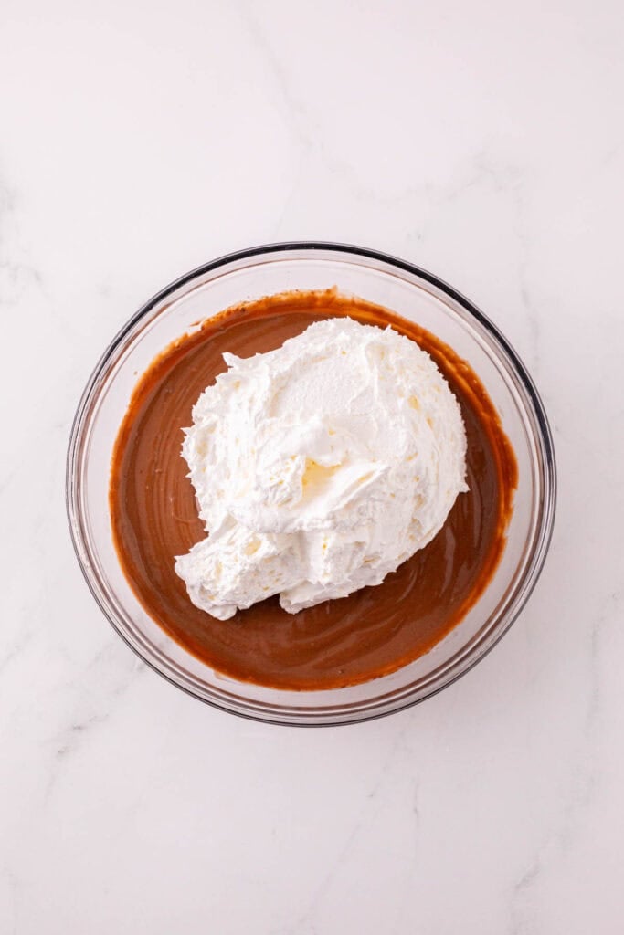 cool whip on top of chocolate pudding in a mixing bowl