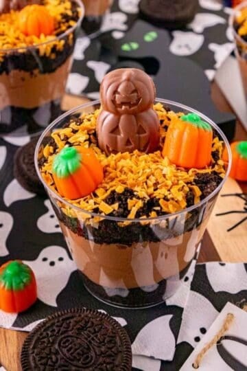These Halloween Dirt Cups are an easy no bake Halloween dessert perfect for parties, kids, and spooky season celebrations! Creamy chocolate peanut butter pudding is layered with crushed Oreo cookies to create delicious Oreo dirt cups, then topped with toasted coconut, mellowcreme pumpkins, and jack o lantern chocolates. If you need easy Halloween desserts, Halloween party food, Halloween treats for kids, or fun Halloween dessert ideas, these pudding dirt cups are a must-try. These Halloween pudding cups take just 15 minutes to prepare and are served in individual cups for an easy party dessert. Make these spooky dirt cups for a Halloween party, school celebration, fall gathering, or movie night. They're a fun twist on classic Oreo dirt pudding and an easy Halloween treat everyone will want to dig into!
