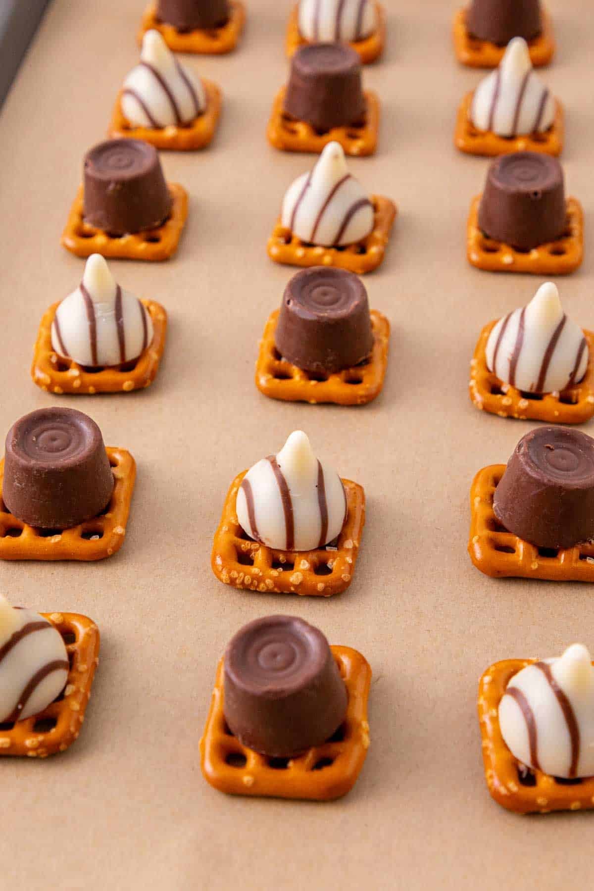 rolos and hershey's hugs on top of pretzels on a baking sheet before baking