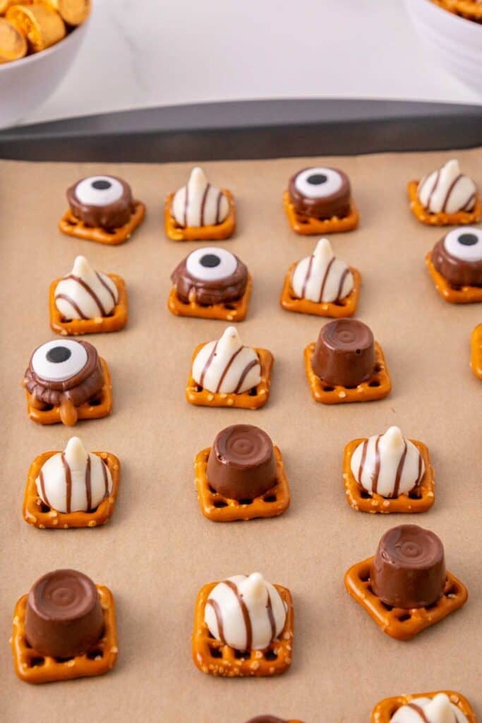 These Halloween Pretzel Rolo Bites are an easy Halloween treat made with crunchy pretzels, gooey Rolo chocolates, Hershey’s Hugs and spooky candy eyes! If you need Easy Halloween Treats, Halloween Pretzel Treats, Halloween Party Food, Halloween Snacks for Kids or quick No Fuss Halloween Desserts, these sweet and salty bites are perfect. They’re ready with just 10 minutes of prep and 3 minutes in the oven, making them a fun choice for Halloween Party Snacks, Classroom Halloween Treats, Halloween Candy Treats and Spooky Halloween Food. Add candy eyeballs to create creepy monster pretzel bites with melted chocolate and caramel. Save these Rolo Pretzel Bites for Halloween Baking Ideas, Easy Halloween Desserts, Kids Halloween Snacks, Halloween Finger Foods and simple Halloween Party Treats everyone will love!