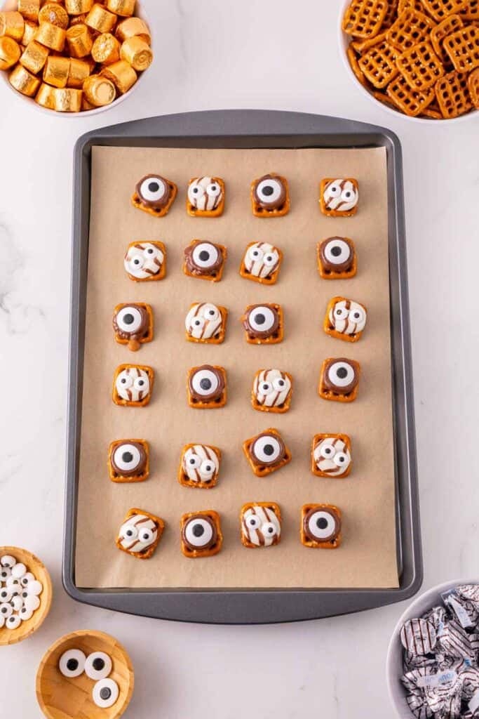 These Halloween Pretzel Rolo Bites are an easy Halloween treat made with crunchy pretzels, gooey Rolo chocolates, Hershey’s Hugs and spooky candy eyes! If you need Easy Halloween Treats, Halloween Pretzel Treats, Halloween Party Food, Halloween Snacks for Kids or quick No Fuss Halloween Desserts, these sweet and salty bites are perfect. They’re ready with just 10 minutes of prep and 3 minutes in the oven, making them a fun choice for Halloween Party Snacks, Classroom Halloween Treats, Halloween Candy Treats and Spooky Halloween Food. Add candy eyeballs to create creepy monster pretzel bites with melted chocolate and caramel. Save these Rolo Pretzel Bites for Halloween Baking Ideas, Easy Halloween Desserts, Kids Halloween Snacks, Halloween Finger Foods and simple Halloween Party Treats everyone will love!