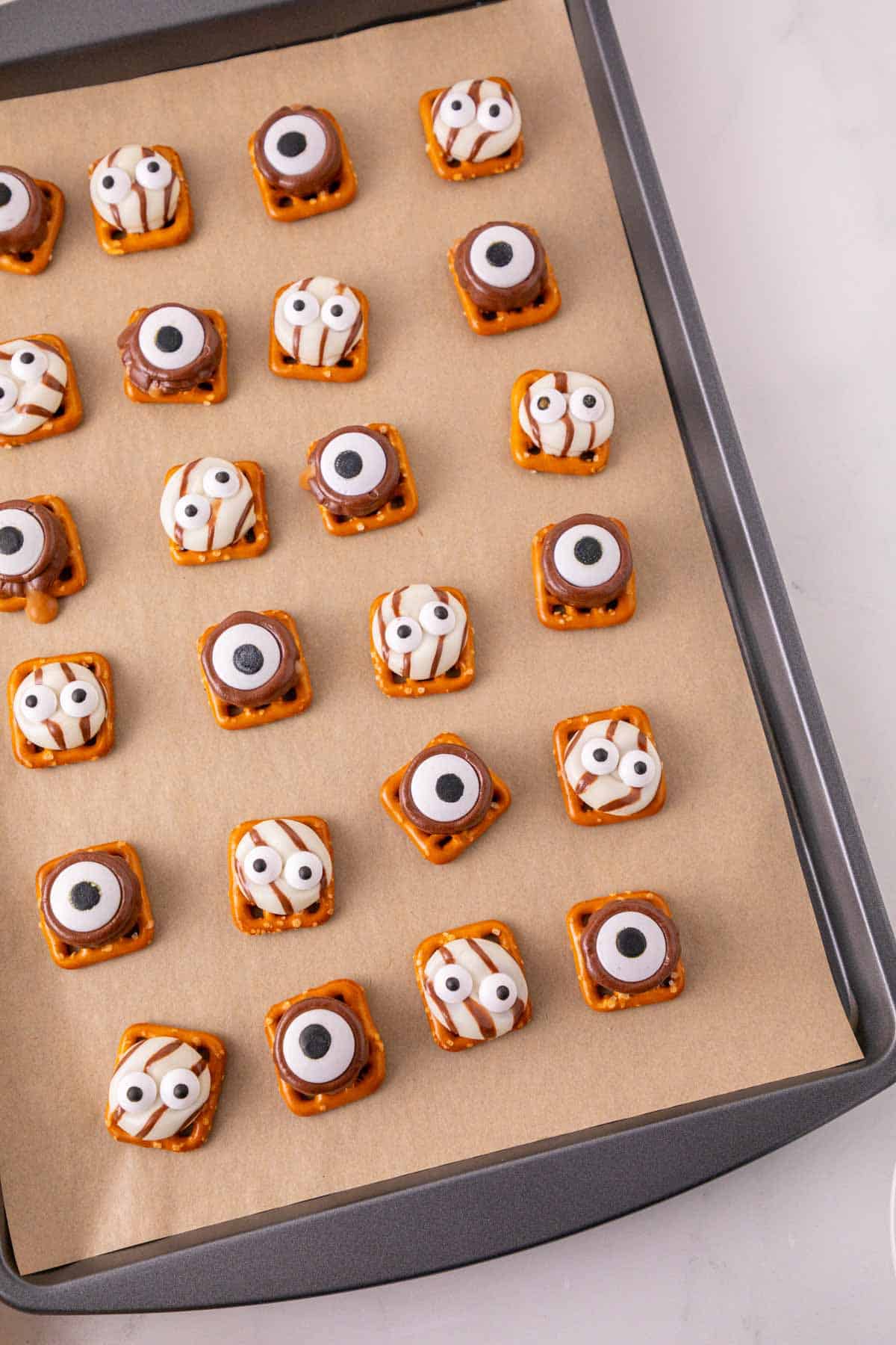 These Halloween Pretzel Rolo Bites are an easy Halloween treat made with crunchy pretzels, gooey Rolo chocolates, Hershey’s Hugs and spooky candy eyes! If you need Easy Halloween Treats, Halloween Pretzel Treats, Halloween Party Food, Halloween Snacks for Kids or quick No Fuss Halloween Desserts, these sweet and salty bites are perfect. They’re ready with just 10 minutes of prep and 3 minutes in the oven, making them a fun choice for Halloween Party Snacks, Classroom Halloween Treats, Halloween Candy Treats and Spooky Halloween Food. Add candy eyeballs to create creepy monster pretzel bites with melted chocolate and caramel. Save these Rolo Pretzel Bites for Halloween Baking Ideas, Easy Halloween Desserts, Kids Halloween Snacks, Halloween Finger Foods and simple Halloween Party Treats everyone will love!