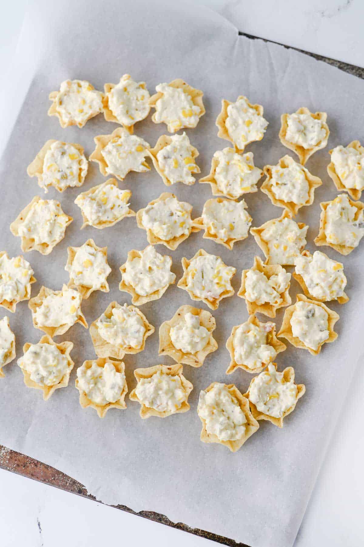 cream cheese corn mixture in tostitos scoops on a baking sheet