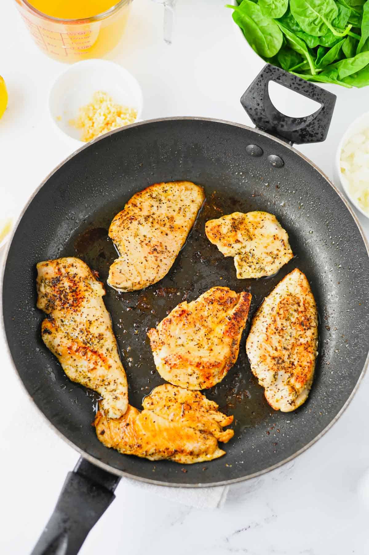 chicken breasts cooking in a skillet