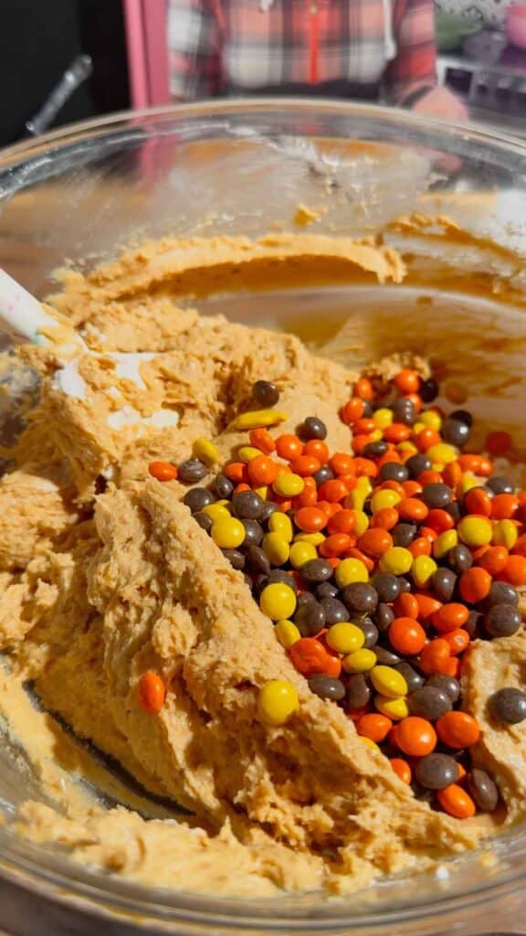 mini reese's pieces added to bowl with peanut butter mixture