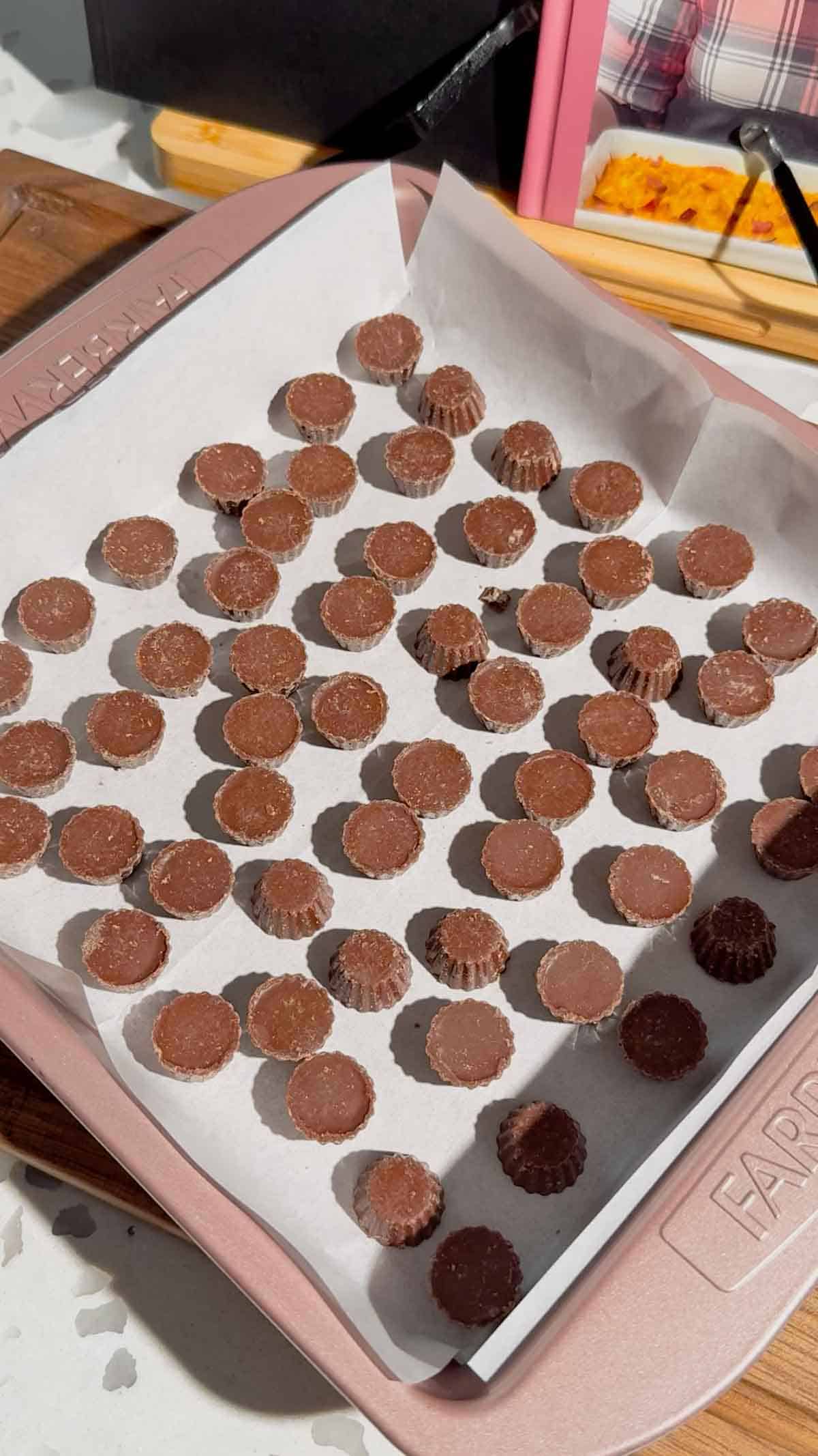 mini reese's peanut butter cups in the bottom of a parchment lined baking pan