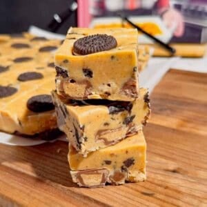 This Oreo Peanut Butter Fudge is the ultimate easy no bake dessert for peanut butter and chocolate lovers! Loaded with mini Reese’s Peanut Butter Cups, creamy peanut butter, peanut butter baking chips, vanilla frosting, and crunchy mini Oreos, this rich homemade fudge is packed with irresistible flavor. If you’re looking for Easy Fudge Recipes, Oreo Desserts, Peanut Butter Desserts, Reese’s Desserts, or No Bake Dessert Recipes, this simple treat is a must-try. Perfect for Christmas Candy, Holiday Desserts, Cookie Exchange Recipes, Party Desserts, Potluck Desserts, and homemade edible gifts, this Microwave Fudge Recipe takes just 15 minutes of prep. Save this Oreo Fudge Recipe when you need an easy dessert that combines cookies and cream with creamy peanut butter and Reese’s candy in every bite!