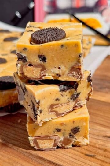 This Oreo Peanut Butter Fudge is the ultimate easy no bake dessert for peanut butter and chocolate lovers! Loaded with mini Reese’s Peanut Butter Cups, creamy peanut butter, peanut butter baking chips, vanilla frosting, and crunchy mini Oreos, this rich homemade fudge is packed with irresistible flavor. If you’re looking for Easy Fudge Recipes, Oreo Desserts, Peanut Butter Desserts, Reese’s Desserts, or No Bake Dessert Recipes, this simple treat is a must-try. Perfect for Christmas Candy, Holiday Desserts, Cookie Exchange Recipes, Party Desserts, Potluck Desserts, and homemade edible gifts, this Microwave Fudge Recipe takes just 15 minutes of prep. Save this Oreo Fudge Recipe when you need an easy dessert that combines cookies and cream with creamy peanut butter and Reese’s candy in every bite!