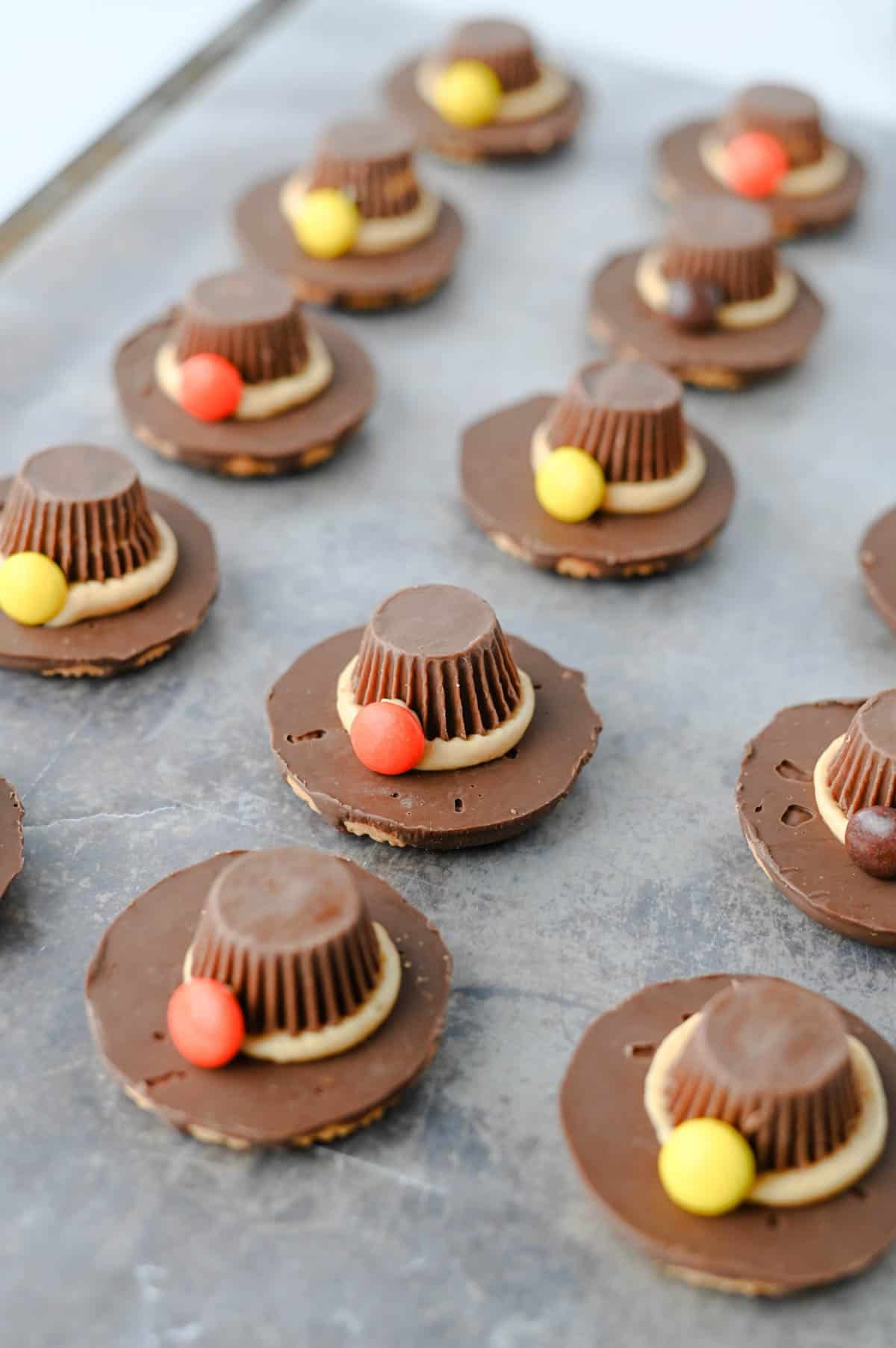 These easy Pilgrim Hat Cookies are the cutest Thanksgiving dessert for your holiday table! Made with Keebler Fudge Stripe cookies, Reese's Peanut Butter Cups, Reese's Pieces and homemade peanut butter frosting, these no bake Thanksgiving cookies are fun, festive and simple to make. With just 20 minutes of prep, this easy Thanksgiving treat is perfect for kids, classroom parties, Friendsgiving, Thanksgiving dinner or a fall dessert table. If you're looking for cute Thanksgiving cookies, easy Thanksgiving desserts, no bake fall treats, Thanksgiving food ideas for kids or simple holiday desserts, these chocolate peanut butter Pilgrim Hat Cookies are a must-try. Save this easy Thanksgiving cookie recipe for a edible craft, party treat or quick Thanksgiving dessert everyone will want to grab!
