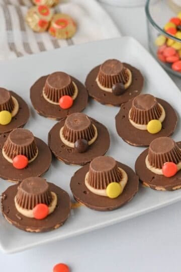 These easy Pilgrim Hat Cookies are the cutest Thanksgiving dessert for your holiday table! Made with Keebler Fudge Stripe cookies, Reese's Peanut Butter Cups, Reese's Pieces and homemade peanut butter frosting, these no bake Thanksgiving cookies are fun, festive and simple to make. With just 20 minutes of prep, this easy Thanksgiving treat is perfect for kids, classroom parties, Friendsgiving, Thanksgiving dinner or a fall dessert table. If you're looking for cute Thanksgiving cookies, easy Thanksgiving desserts, no bake fall treats, Thanksgiving food ideas for kids or simple holiday desserts, these chocolate peanut butter Pilgrim Hat Cookies are a must-try. Save this easy Thanksgiving cookie recipe for a edible craft, party treat or quick Thanksgiving dessert everyone will want to grab!