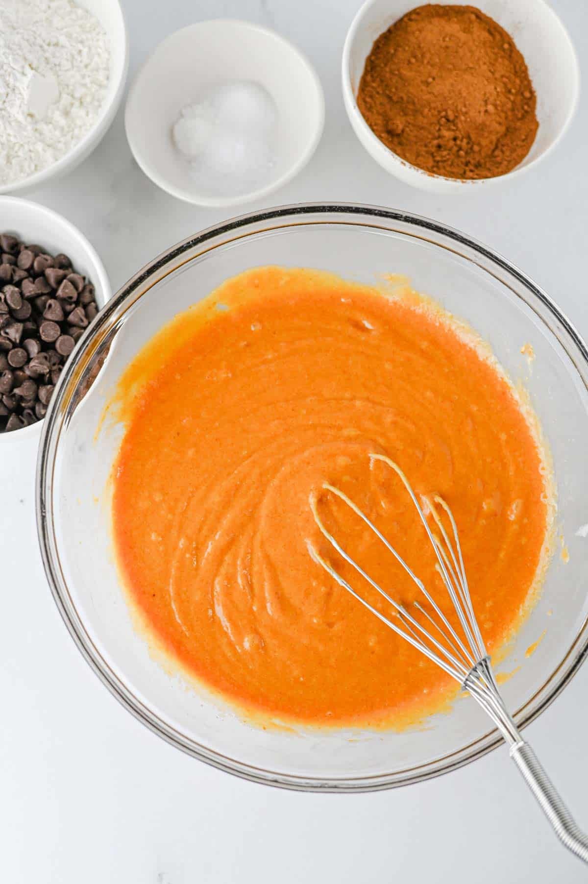 pumpkin puree and other wet ingredients whisked together in a glass mixing bowl