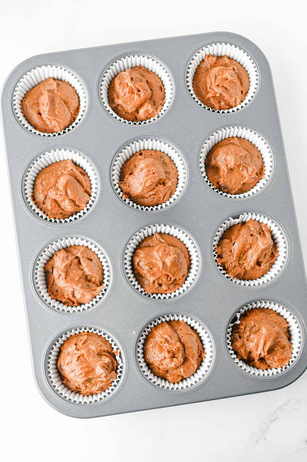 pumpkin chocolate muffin batter in a muffin tin