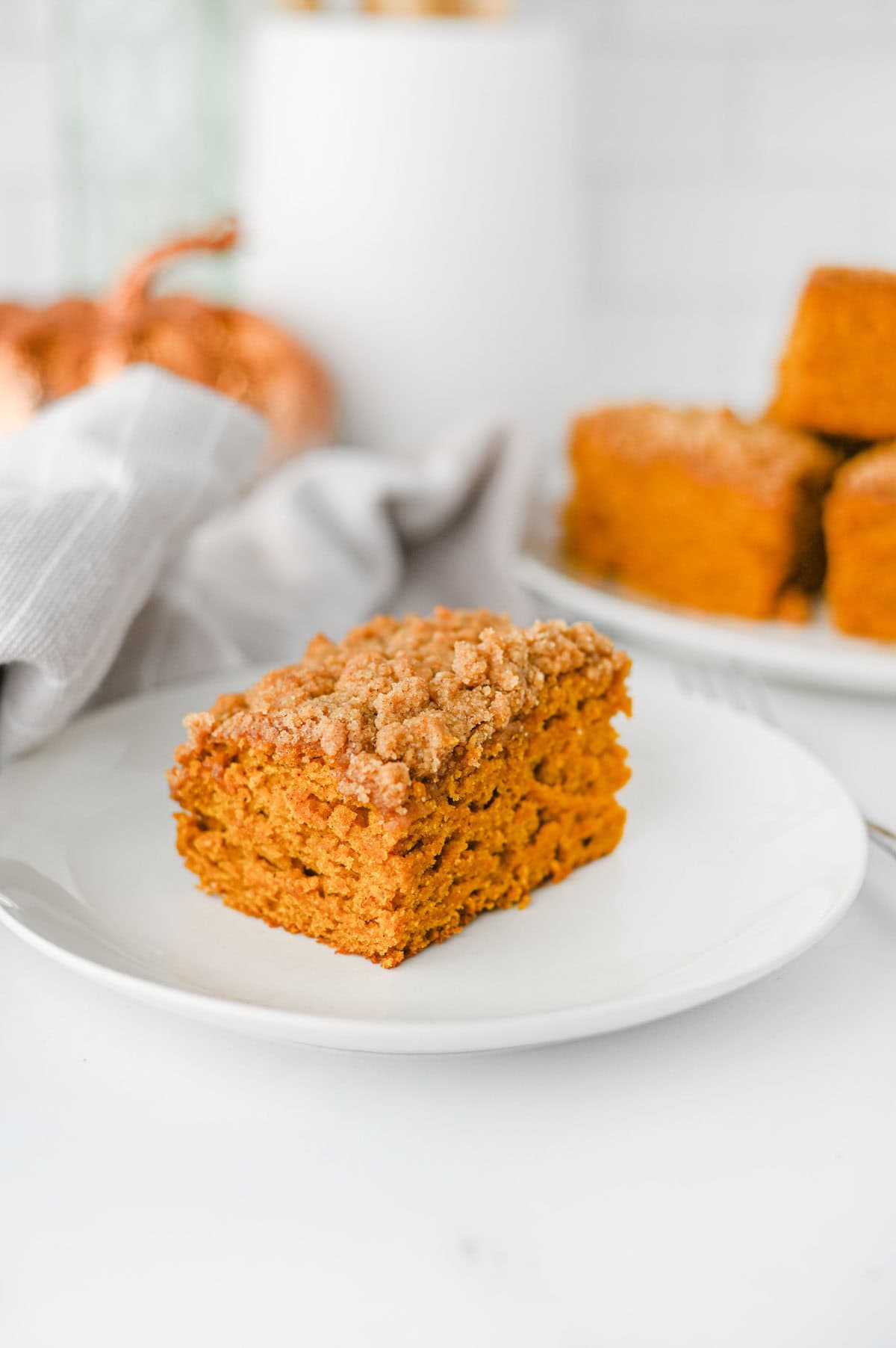 This Pumpkin Coffee Cake is the ultimate cozy fall baking recipe, made with pumpkin puree, warm cinnamon, nutmeg, ginger, brown sugar, and a touch of maple syrup. This easy Pumpkin Coffee Cake Recipe is soft, moist, and topped with a buttery cinnamon brown sugar crumb topping for the perfect sweet crunch. Add the simple powdered sugar icing for an extra decadent finish! If you're looking for Easy Pumpkin Desserts, Pumpkin Breakfast Recipes, Fall Baking Ideas, Pumpkin Spice Recipes, or delicious Fall Brunch Recipes, this homemade coffee cake is a must-try. It's perfect for Thanksgiving breakfast, holiday brunch, weekend baking, or enjoying with a hot cup of coffee. Save this Easy Pumpkin Coffee Cake for pumpkin season when you need a simple Pumpkin Dessert that's packed with cozy fall flavor!