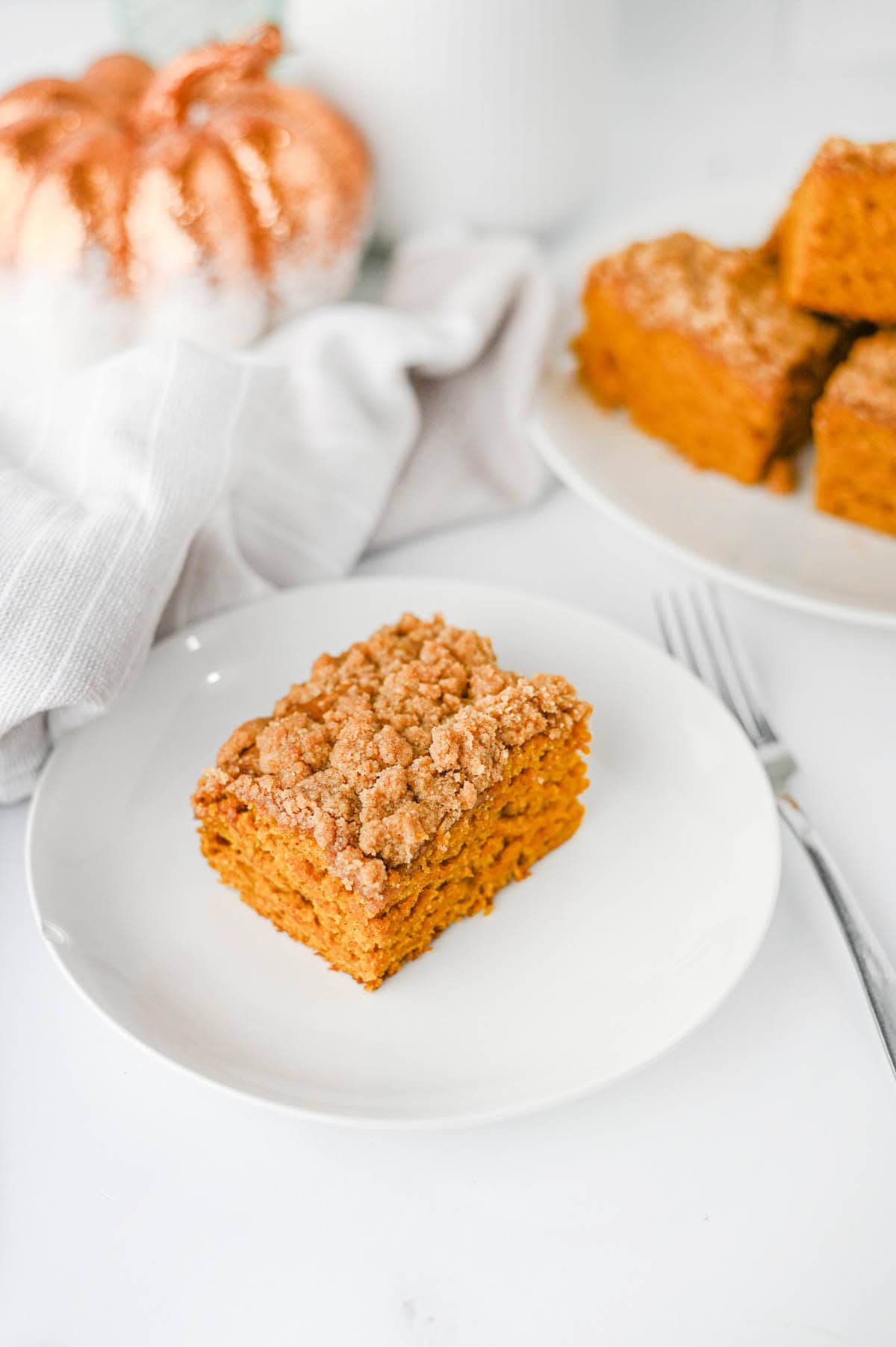 This Pumpkin Coffee Cake is the ultimate cozy fall baking recipe, made with pumpkin puree, warm cinnamon, nutmeg, ginger, brown sugar, and a touch of maple syrup. This easy Pumpkin Coffee Cake Recipe is soft, moist, and topped with a buttery cinnamon brown sugar crumb topping for the perfect sweet crunch. Add the simple powdered sugar icing for an extra decadent finish! If you're looking for Easy Pumpkin Desserts, Pumpkin Breakfast Recipes, Fall Baking Ideas, Pumpkin Spice Recipes, or delicious Fall Brunch Recipes, this homemade coffee cake is a must-try. It's perfect for Thanksgiving breakfast, holiday brunch, weekend baking, or enjoying with a hot cup of coffee. Save this Easy Pumpkin Coffee Cake for pumpkin season when you need a simple Pumpkin Dessert that's packed with cozy fall flavor!