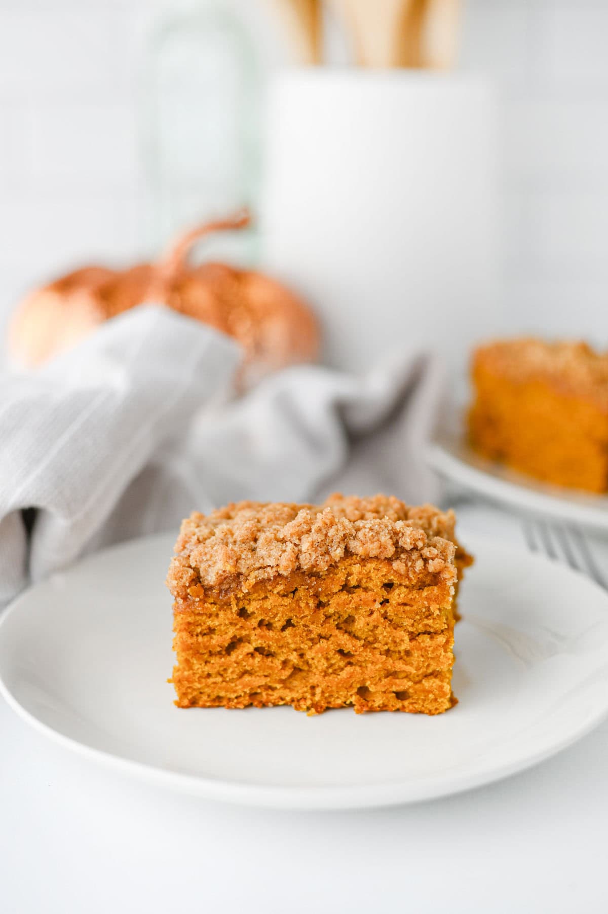 This Pumpkin Coffee Cake is the ultimate cozy fall baking recipe, made with pumpkin puree, warm cinnamon, nutmeg, ginger, brown sugar, and a touch of maple syrup. This easy Pumpkin Coffee Cake Recipe is soft, moist, and topped with a buttery cinnamon brown sugar crumb topping for the perfect sweet crunch. Add the simple powdered sugar icing for an extra decadent finish! If you're looking for Easy Pumpkin Desserts, Pumpkin Breakfast Recipes, Fall Baking Ideas, Pumpkin Spice Recipes, or delicious Fall Brunch Recipes, this homemade coffee cake is a must-try. It's perfect for Thanksgiving breakfast, holiday brunch, weekend baking, or enjoying with a hot cup of coffee. Save this Easy Pumpkin Coffee Cake for pumpkin season when you need a simple Pumpkin Dessert that's packed with cozy fall flavor!