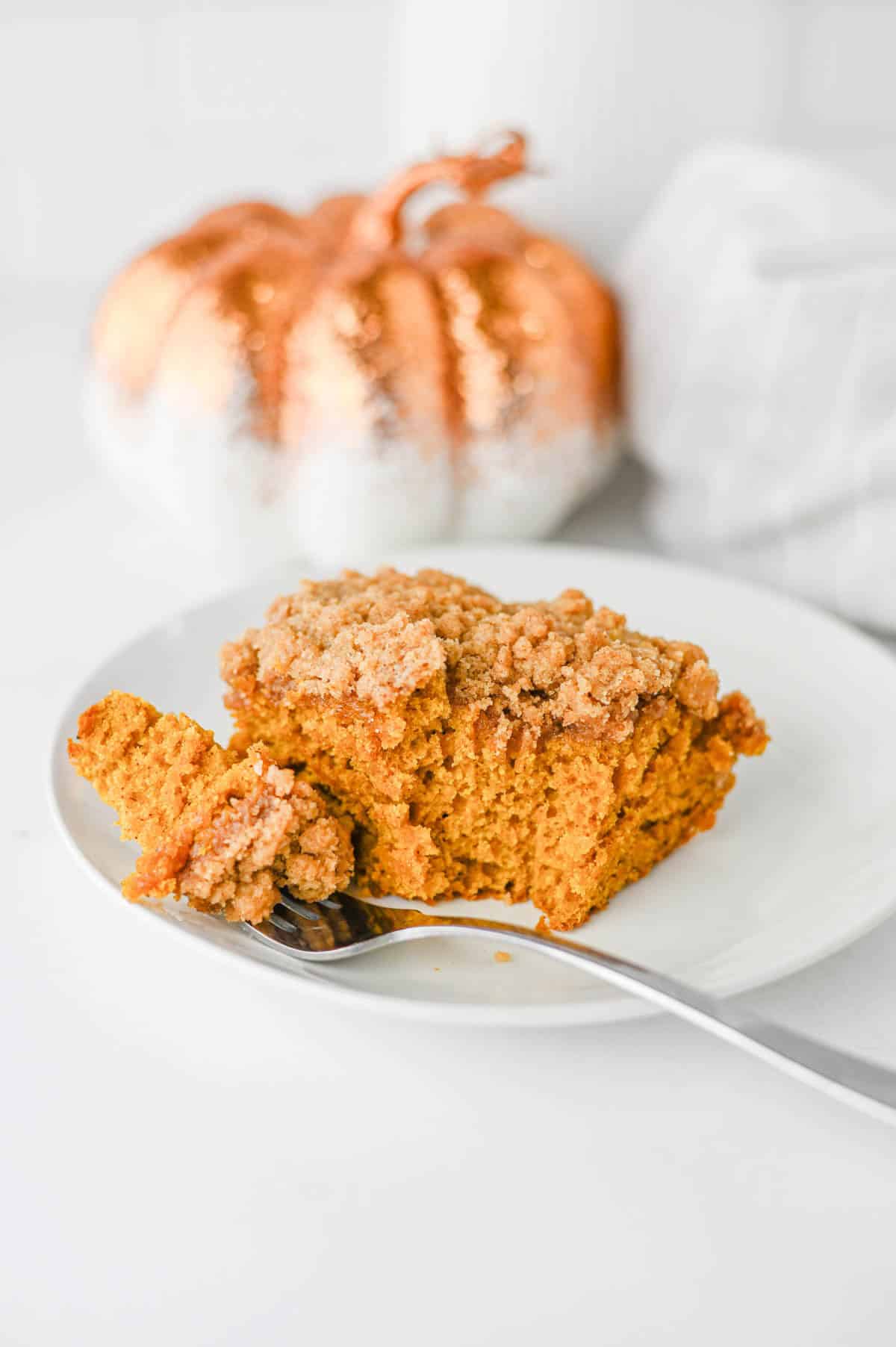 This Pumpkin Coffee Cake is the ultimate cozy fall baking recipe, made with pumpkin puree, warm cinnamon, nutmeg, ginger, brown sugar, and a touch of maple syrup. This easy Pumpkin Coffee Cake Recipe is soft, moist, and topped with a buttery cinnamon brown sugar crumb topping for the perfect sweet crunch. Add the simple powdered sugar icing for an extra decadent finish! If you're looking for Easy Pumpkin Desserts, Pumpkin Breakfast Recipes, Fall Baking Ideas, Pumpkin Spice Recipes, or delicious Fall Brunch Recipes, this homemade coffee cake is a must-try. It's perfect for Thanksgiving breakfast, holiday brunch, weekend baking, or enjoying with a hot cup of coffee. Save this Easy Pumpkin Coffee Cake for pumpkin season when you need a simple Pumpkin Dessert that's packed with cozy fall flavor!