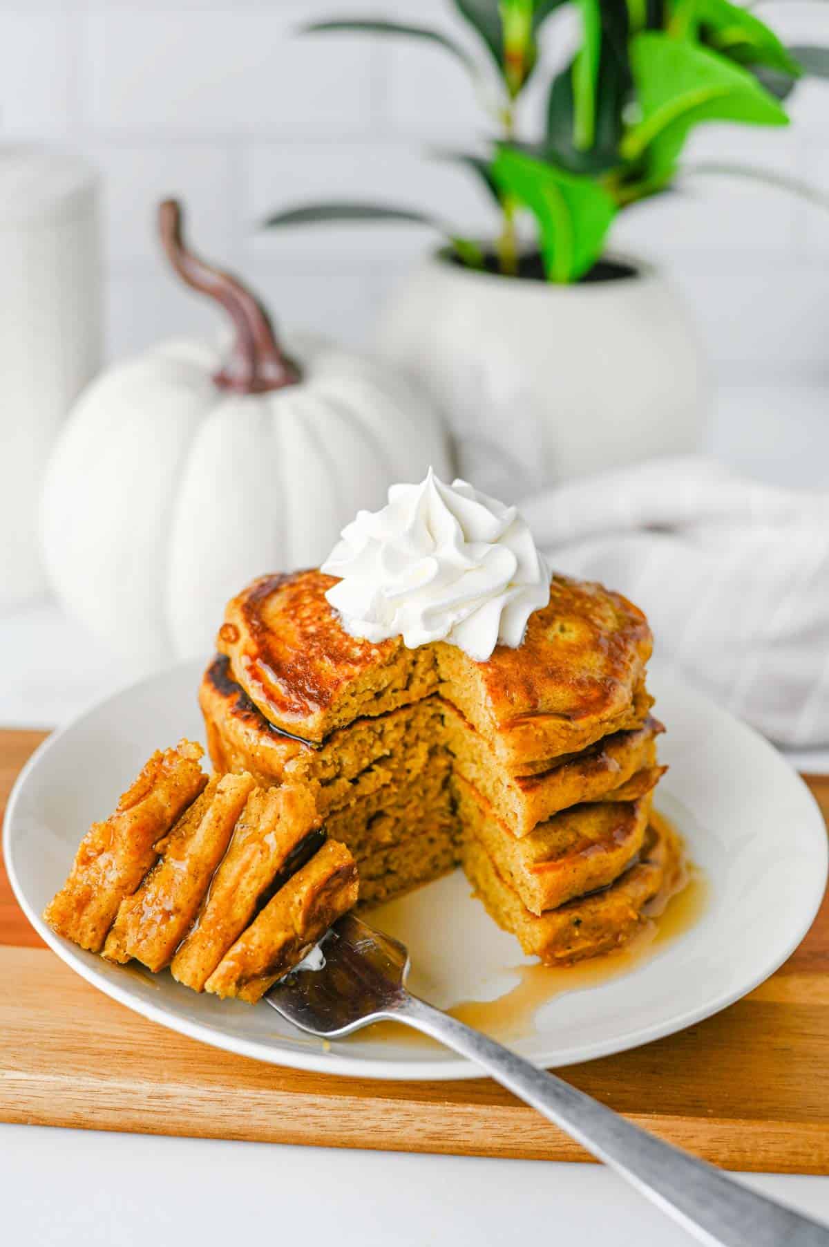 These fluffy Pumpkin Pancakes are the ultimate cozy fall breakfast, made with pumpkin puree, pumpkin pie spice, cinnamon, brown sugar and melted butter for warm autumn flavor in every bite. This easy Pumpkin Pancakes Recipe makes soft, thick and fluffy pancakes that are perfect for weekend breakfasts, Thanksgiving morning, Halloween breakfast or a fall brunch. If you're looking for Easy Pumpkin Pancakes, Pumpkin Breakfast Recipes, Fall Breakfast Ideas or recipes using pumpkin puree, save this one! Top these homemade pumpkin pancakes with butter, maple syrup, whipped cream, chopped pecans or walnuts and an extra sprinkle of pumpkin pie spice. These Pumpkin Spice Pancakes are an easy way to use canned pumpkin and make a delicious breakfast for the whole family during pumpkin season.
