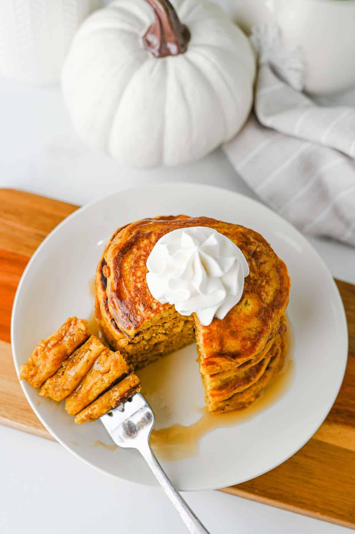These fluffy Pumpkin Pancakes are the ultimate cozy fall breakfast, made with pumpkin puree, pumpkin pie spice, cinnamon, brown sugar and melted butter for warm autumn flavor in every bite. This easy Pumpkin Pancakes Recipe makes soft, thick and fluffy pancakes that are perfect for weekend breakfasts, Thanksgiving morning, Halloween breakfast or a fall brunch. If you're looking for Easy Pumpkin Pancakes, Pumpkin Breakfast Recipes, Fall Breakfast Ideas or recipes using pumpkin puree, save this one! Top these homemade pumpkin pancakes with butter, maple syrup, whipped cream, chopped pecans or walnuts and an extra sprinkle of pumpkin pie spice. These Pumpkin Spice Pancakes are an easy way to use canned pumpkin and make a delicious breakfast for the whole family during pumpkin season.