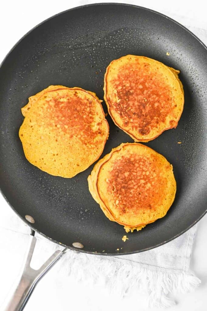 pumpkin pancakes cooking in a skillet
