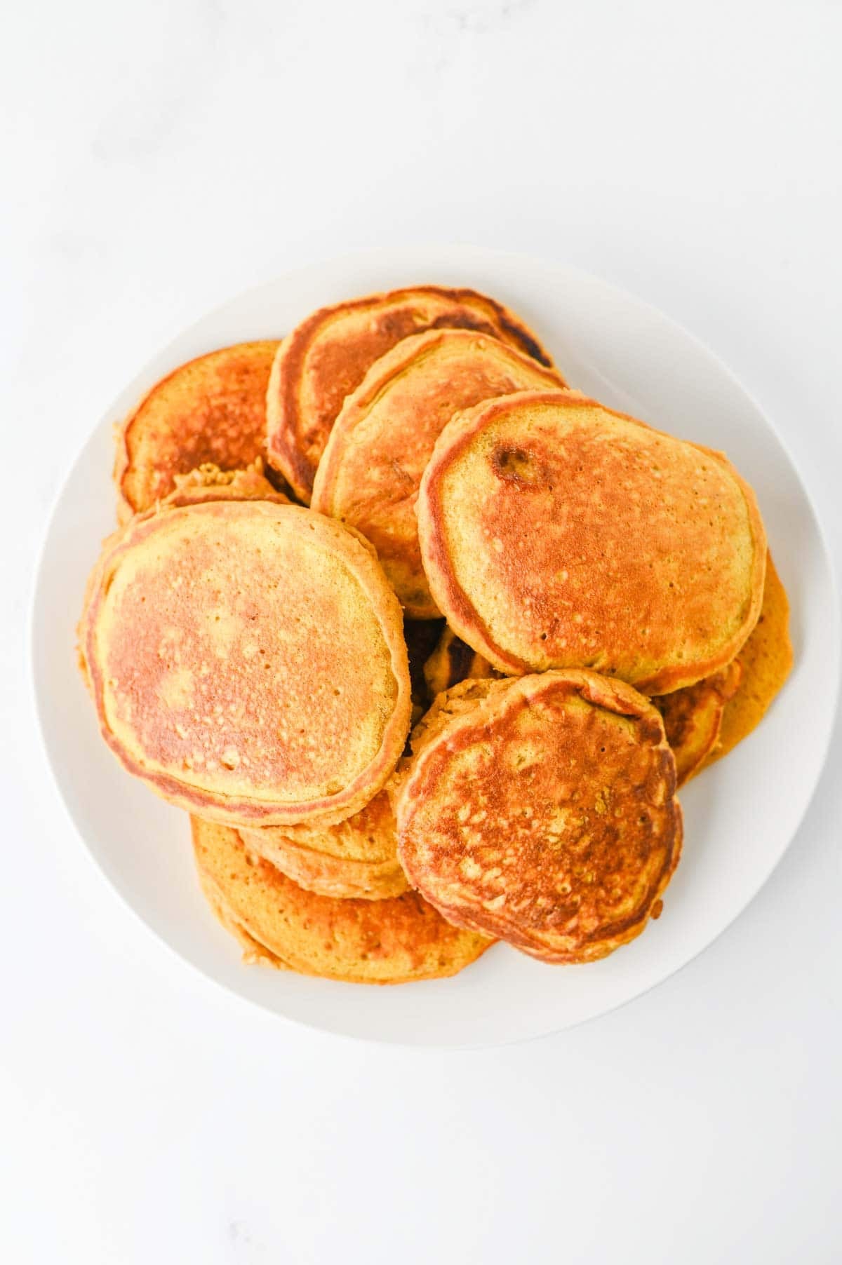 These fluffy Pumpkin Pancakes are the ultimate cozy fall breakfast, made with pumpkin puree, pumpkin pie spice, cinnamon, brown sugar and melted butter for warm autumn flavor in every bite. This easy Pumpkin Pancakes Recipe makes soft, thick and fluffy pancakes that are perfect for weekend breakfasts, Thanksgiving morning, Halloween breakfast or a fall brunch. If you're looking for Easy Pumpkin Pancakes, Pumpkin Breakfast Recipes, Fall Breakfast Ideas or recipes using pumpkin puree, save this one! Top these homemade pumpkin pancakes with butter, maple syrup, whipped cream, chopped pecans or walnuts and an extra sprinkle of pumpkin pie spice. These Pumpkin Spice Pancakes are an easy way to use canned pumpkin and make a delicious breakfast for the whole family during pumpkin season.