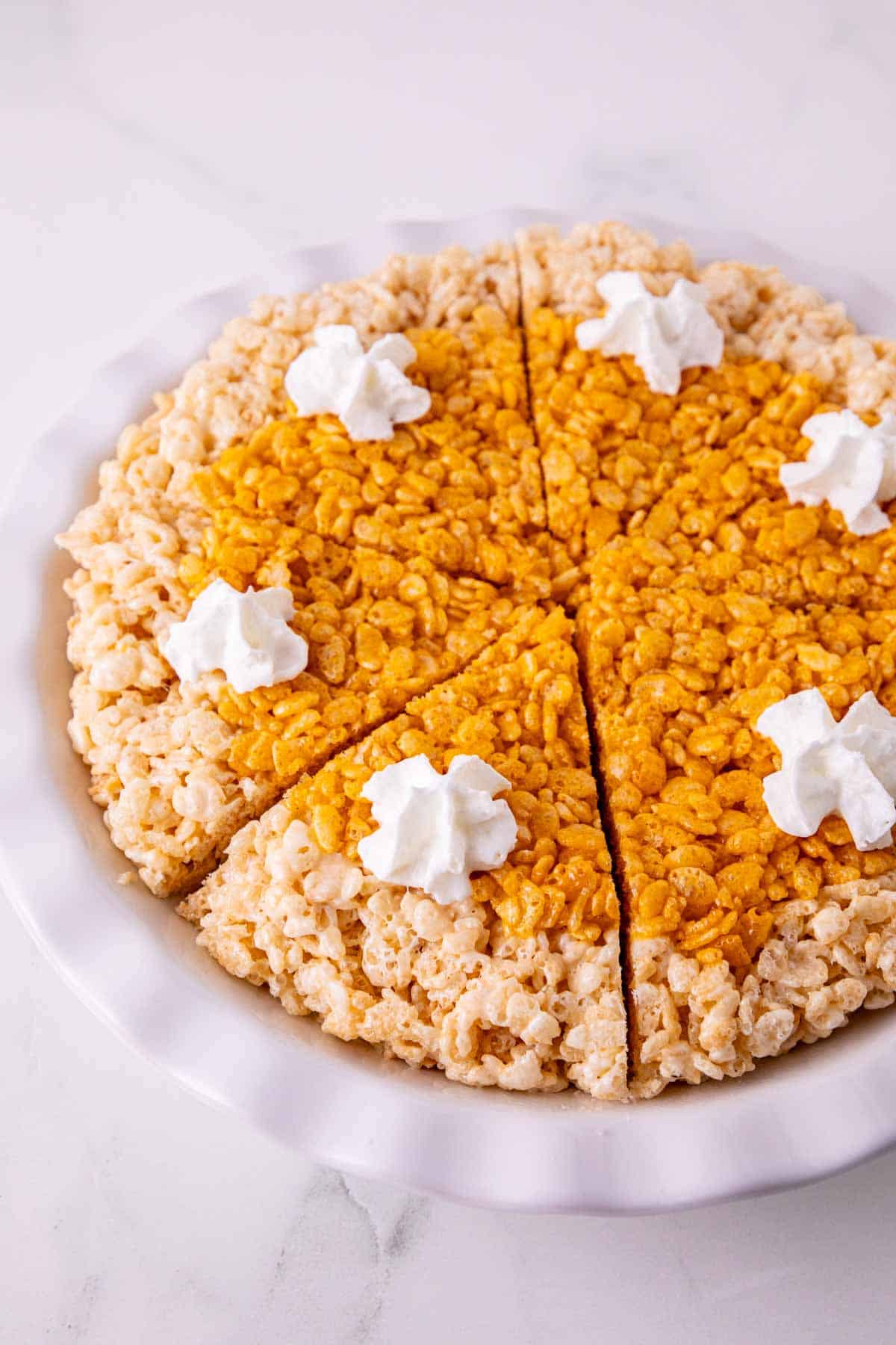 These Pumpkin Rice Krispie Treats are a fun fall dessert that turns classic marshmallow cereal treats into an adorable pumpkin pie! Made with buttery Rice Krispies, pumpkin puree, pumpkin pie spice and orange food coloring, this easy no bake dessert is perfect for Halloween parties, Thanksgiving dessert tables and fall gatherings. If you’re looking for easy pumpkin desserts, Halloween Rice Krispie treats, no bake fall desserts or easy fall treats for kids, this festive recipe is a must-try. The crispy Rice Krispie crust surrounds a soft, chewy pumpkin-spiced center that looks just like pumpkin pie. Add whipped topping before serving for a festive finish everyone will love. Save these Pumpkin Rice Krispie Treats for your fall baking, Halloween dessert and Thanksgiving treat ideas!