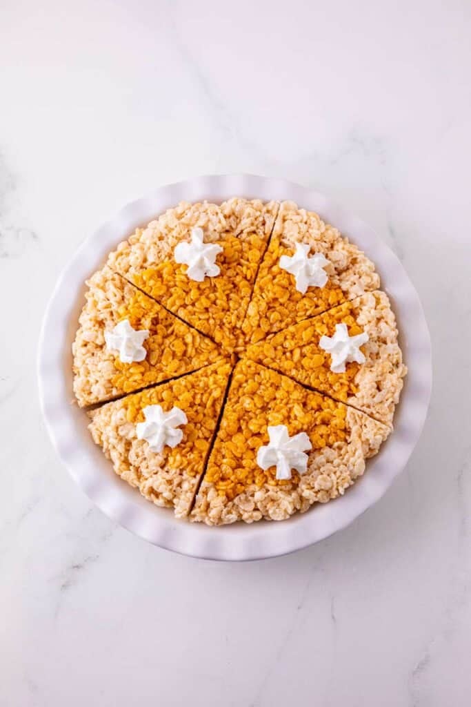These Pumpkin Rice Krispie Treats are a fun fall dessert that turns classic marshmallow cereal treats into an adorable pumpkin pie! Made with buttery Rice Krispies, pumpkin puree, pumpkin pie spice and orange food coloring, this easy no bake dessert is perfect for Halloween parties, Thanksgiving dessert tables and fall gatherings. If you’re looking for easy pumpkin desserts, Halloween Rice Krispie treats, no bake fall desserts or easy fall treats for kids, this festive recipe is a must-try. The crispy Rice Krispie crust surrounds a soft, chewy pumpkin-spiced center that looks just like pumpkin pie. Add whipped topping before serving for a festive finish everyone will love. Save these Pumpkin Rice Krispie Treats for your fall baking, Halloween dessert and Thanksgiving treat ideas!