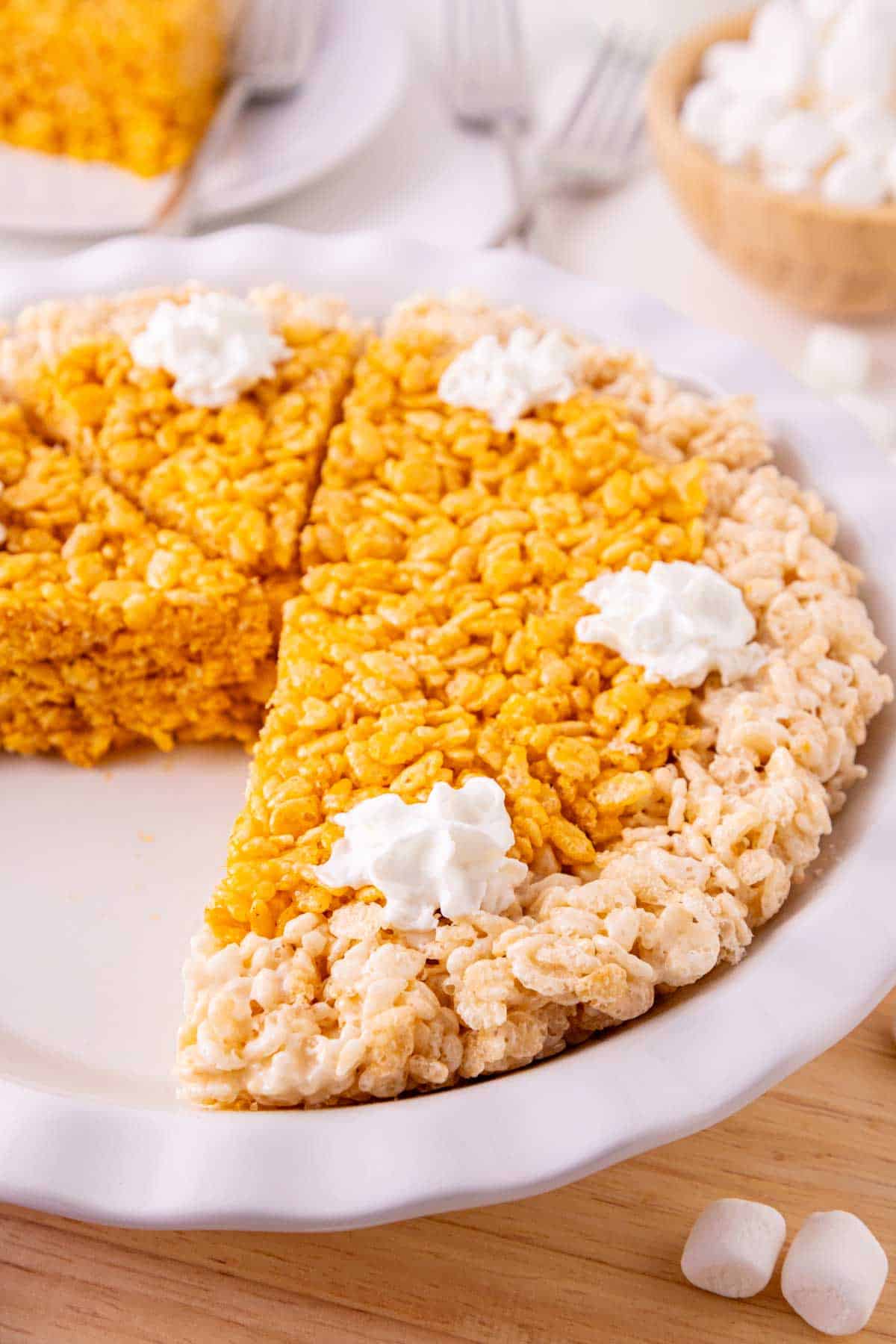 These Pumpkin Rice Krispie Treats are a fun fall dessert that turns classic marshmallow cereal treats into an adorable pumpkin pie! Made with buttery Rice Krispies, pumpkin puree, pumpkin pie spice and orange food coloring, this easy no bake dessert is perfect for Halloween parties, Thanksgiving dessert tables and fall gatherings. If you’re looking for easy pumpkin desserts, Halloween Rice Krispie treats, no bake fall desserts or easy fall treats for kids, this festive recipe is a must-try. The crispy Rice Krispie crust surrounds a soft, chewy pumpkin-spiced center that looks just like pumpkin pie. Add whipped topping before serving for a festive finish everyone will love. Save these Pumpkin Rice Krispie Treats for your fall baking, Halloween dessert and Thanksgiving treat ideas!
