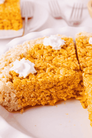 These Pumpkin Rice Krispie Treats are a fun fall dessert that turns classic marshmallow cereal treats into an adorable pumpkin pie! Made with buttery Rice Krispies, pumpkin puree, pumpkin pie spice and orange food coloring, this easy no bake dessert is perfect for Halloween parties, Thanksgiving dessert tables and fall gatherings. If you’re looking for easy pumpkin desserts, Halloween Rice Krispie treats, no bake fall desserts or easy fall treats for kids, this festive recipe is a must-try. The crispy Rice Krispie crust surrounds a soft, chewy pumpkin-spiced center that looks just like pumpkin pie. Add whipped topping before serving for a festive finish everyone will love. Save these Pumpkin Rice Krispie Treats for your fall baking, Halloween dessert and Thanksgiving treat ideas!
