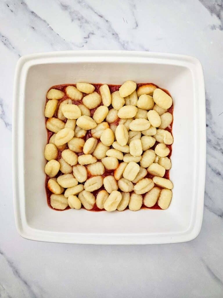 potato gnocchi on top of tomato sauce in a baking dish