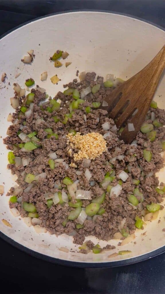 chopped garlic on top of cooked ground beef in a pot