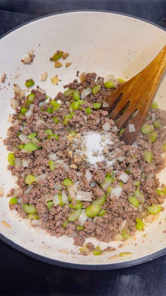 seasonings on top of cooked ground beef in a large pot
