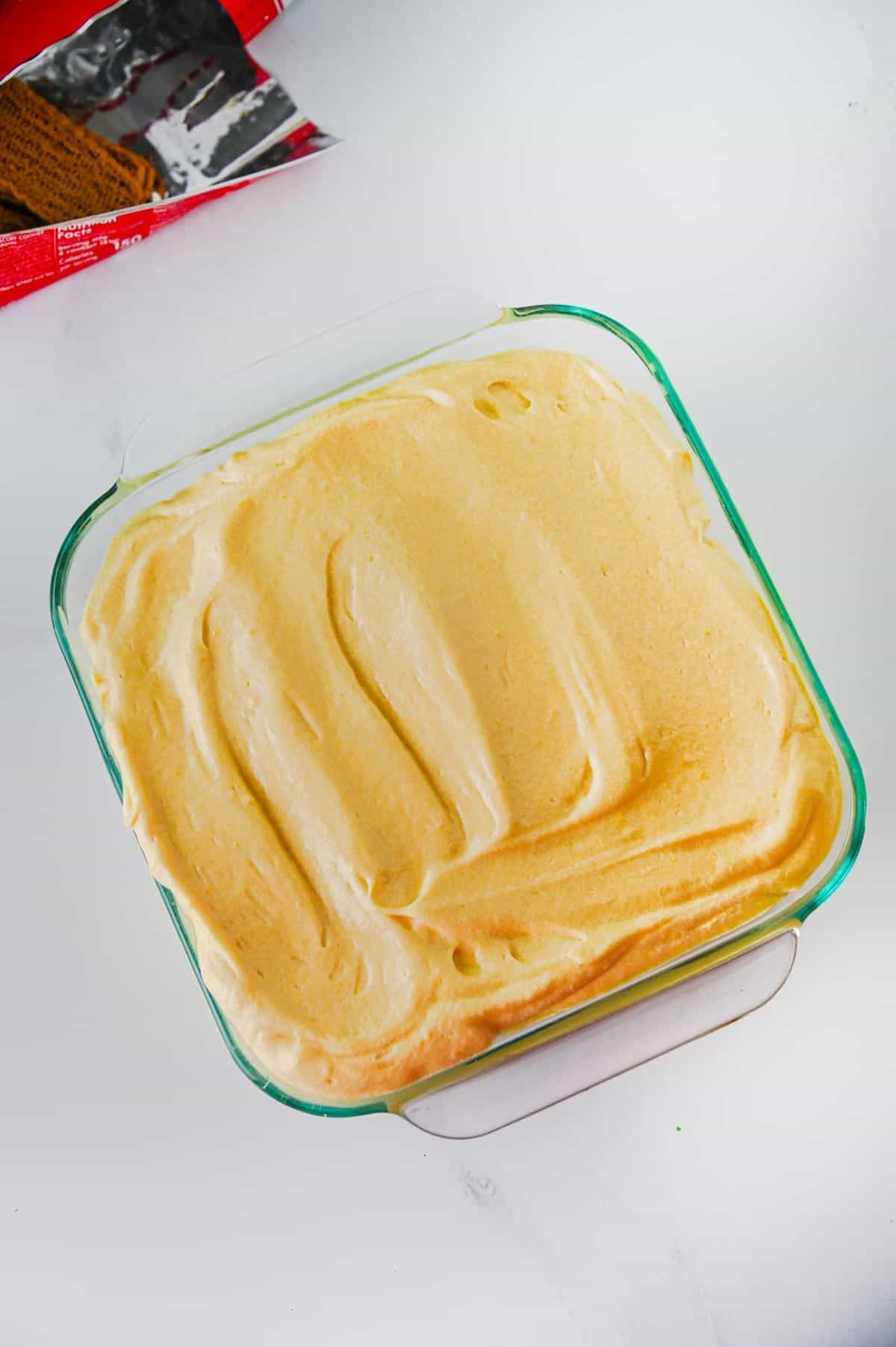 cookie butter pudding on top of bananas and cookies in a bakig dish