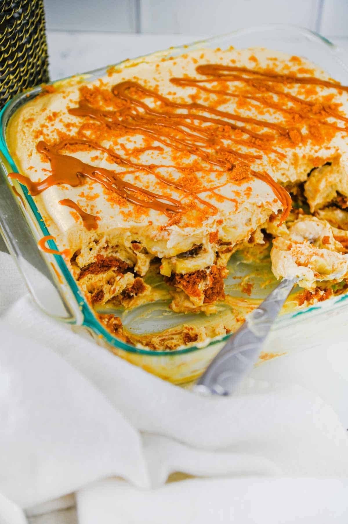 biscoff banana pudding topped with cookie butter drizzle in a baking dish