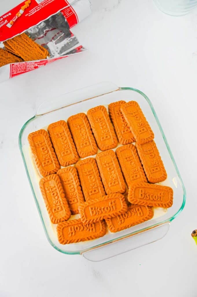 biscoff cookies on top of pudding mixture in a baking dish