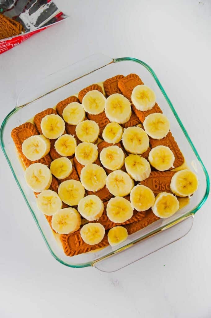 sliced bananas on top of biscoff cookies in a baking dish