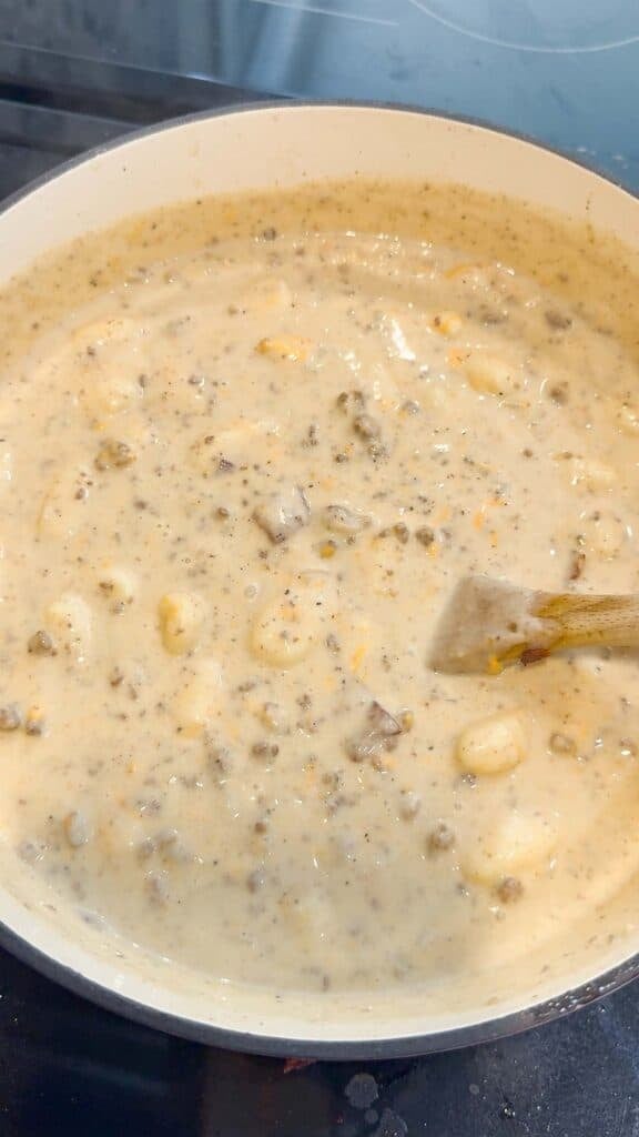 stirring creamy beef gnocchi soup in a pot