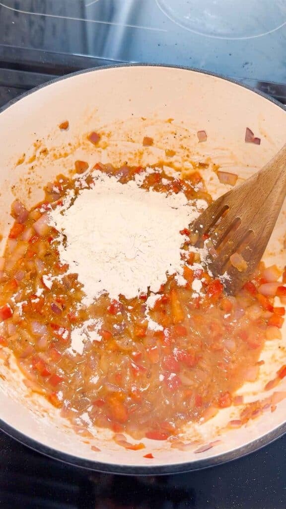flour added to pot with cooked red onions and bell peppers