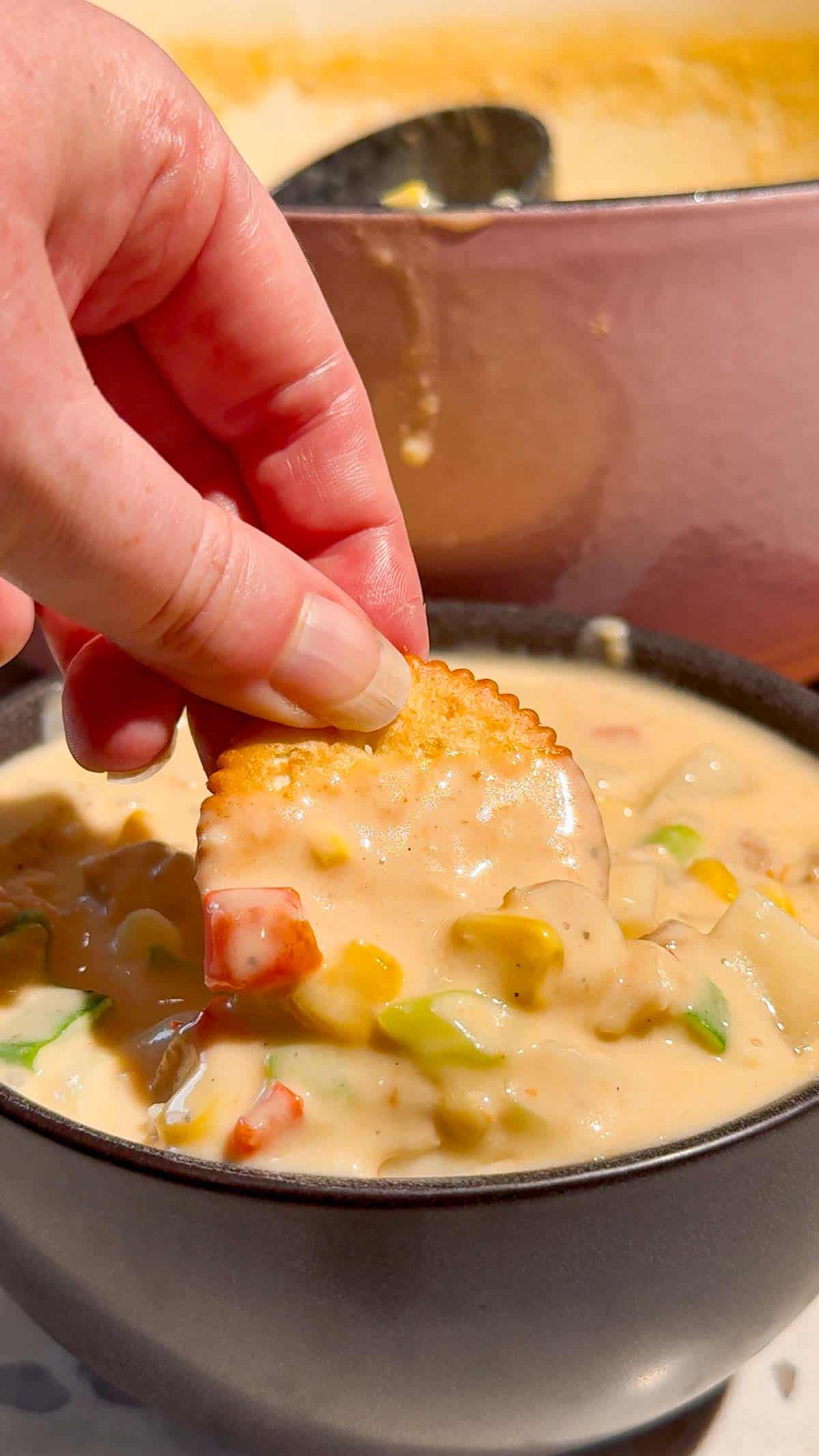 Ritz cracker being dipped in chicken corn chowder
