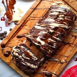 This Chocolate Loaf Cake is a rich, moist and decadent dessert that's perfect for chocolate lovers! This easy Chocolate Loaf Cake Recipe is made with cocoa powder, buttermilk and dark chocolate chips for a soft, tender crumb packed with chocolate flavor. Topped with a dark chocolate and white chocolate drizzle, this homemade chocolate bread makes an impressive but simple dessert for any occasion. If you're looking for Easy Loaf Cake Recipes, Chocolate Dessert Recipes, Chocolate Bread Recipes, Easy Baking Recipes or a Moist Chocolate Cake Recipe, this one belongs on your baking list. Serve this Chocolate Chip Loaf Cake for birthdays, holidays, afternoon treats, brunch or dessert. It's an easy chocolate cake that's delicious with coffee, tea or a glass of milk and perfect for sharing!