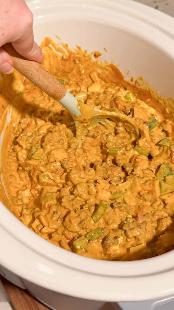 These Crock Pot Nachos are easy game day food, party appetizer or fun family dinner loaded with bold Tex-Mex flavor. This easy slow cooker nachos recipe combines seasoned ground beef, Italian sausage, onions, green peppers, Rotel, salsa con queso, cream cheese and shredded cheese for an extra creamy, meaty nacho topping. Spoon the cheesy Crock Pot nacho mixture over tortilla chips or Doritos, then add sour cream, guacamole, diced tomatoes, cilantro and jalapenos. If you need easy Crock Pot appetizers, slow cooker party food, football food ideas, Super Bowl snacks, nacho recipes or easy appetizers for a crowd, save this recipe. These loaded nachos are perfect for game day parties, potlucks, movie nights and casual entertaining when you want easy comfort food everyone will dig into!