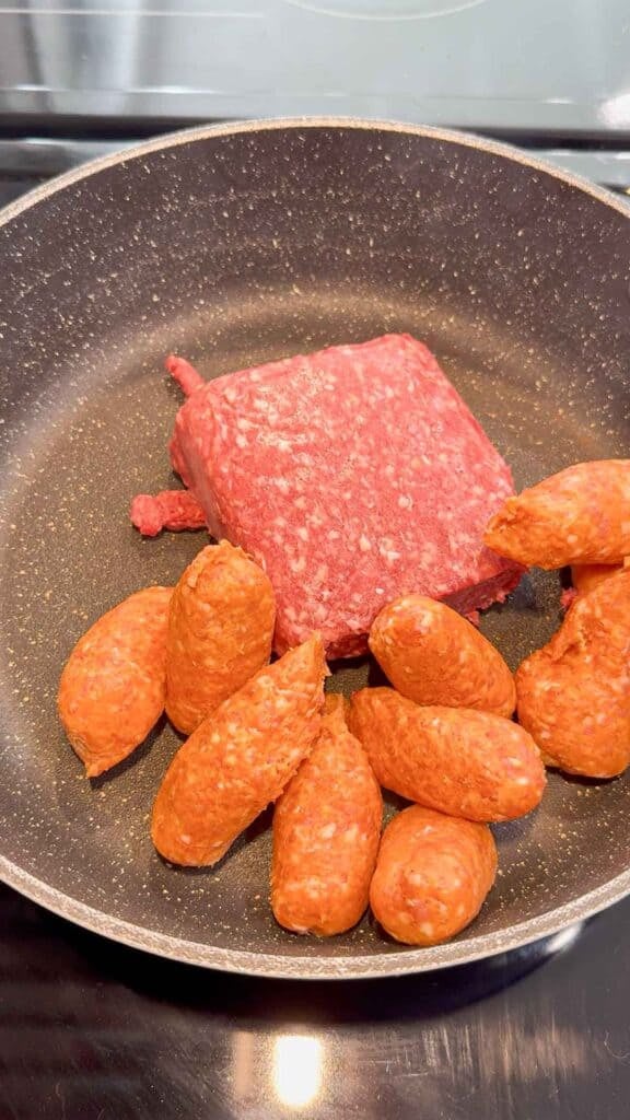raw ground beef and sausage meat in a skillet