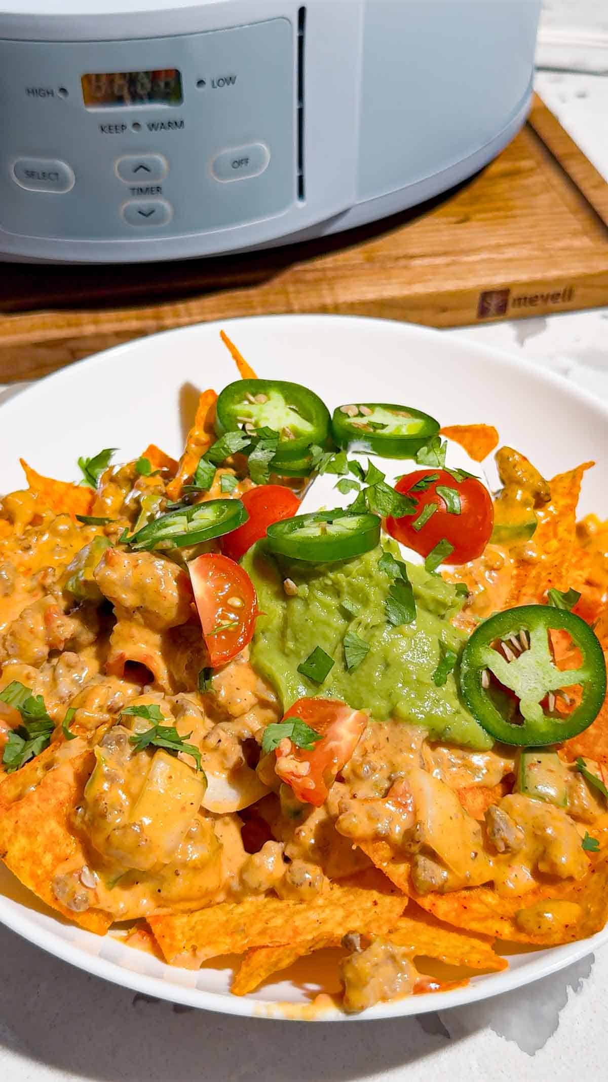 These Crock Pot Nachos are easy game day food, party appetizer or fun family dinner loaded with bold Tex-Mex flavor. This easy slow cooker nachos recipe combines seasoned ground beef, Italian sausage, onions, green peppers, Rotel, salsa con queso, cream cheese and shredded cheese for an extra creamy, meaty nacho topping. Spoon the cheesy Crock Pot nacho mixture over tortilla chips or Doritos, then add sour cream, guacamole, diced tomatoes, cilantro and jalapenos. If you need easy Crock Pot appetizers, slow cooker party food, football food ideas, Super Bowl snacks, nacho recipes or easy appetizers for a crowd, save this recipe. These loaded nachos are perfect for game day parties, potlucks, movie nights and casual entertaining when you want easy comfort food everyone will dig into!