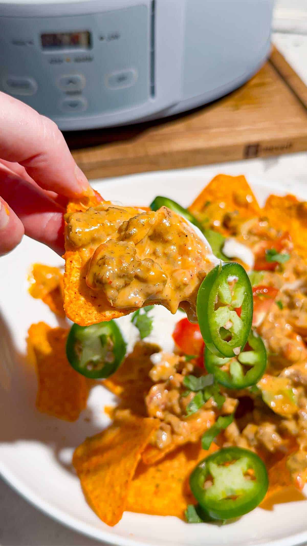 These Crock Pot Nachos are easy game day food, party appetizer or fun family dinner loaded with bold Tex-Mex flavor. This easy slow cooker nachos recipe combines seasoned ground beef, Italian sausage, onions, green peppers, Rotel, salsa con queso, cream cheese and shredded cheese for an extra creamy, meaty nacho topping. Spoon the cheesy Crock Pot nacho mixture over tortilla chips or Doritos, then add sour cream, guacamole, diced tomatoes, cilantro and jalapenos. If you need easy Crock Pot appetizers, slow cooker party food, football food ideas, Super Bowl snacks, nacho recipes or easy appetizers for a crowd, save this recipe. These loaded nachos are perfect for game day parties, potlucks, movie nights and casual entertaining when you want easy comfort food everyone will dig into!