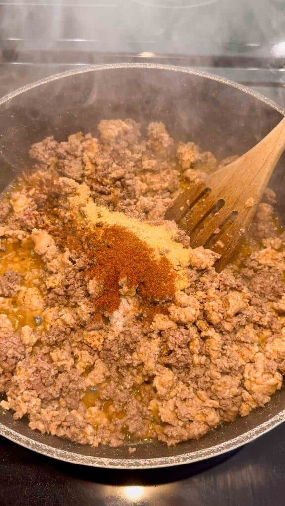 seasonings added to skillet with cooked ground beef and sausage meat